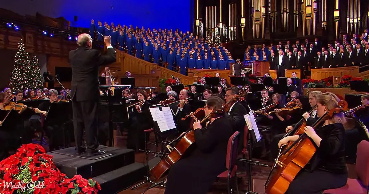 Conductor leads orchestra and choir in a festive performance with Christmas decorations.