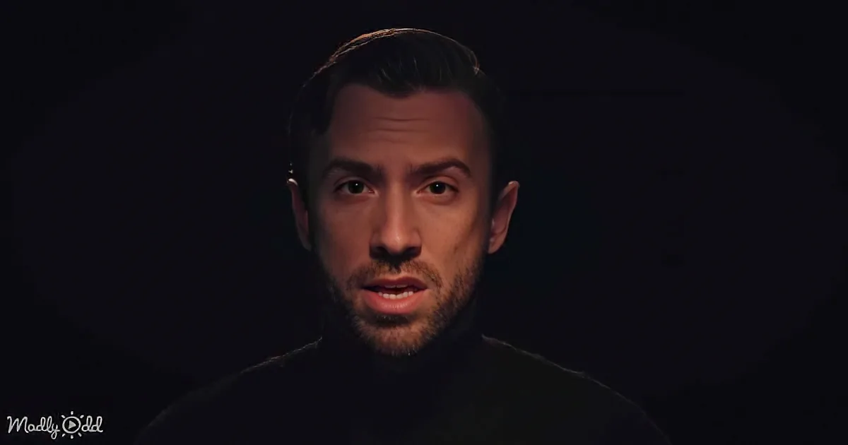 A man with short hair, a beard, and a black turtleneck against a dark background.