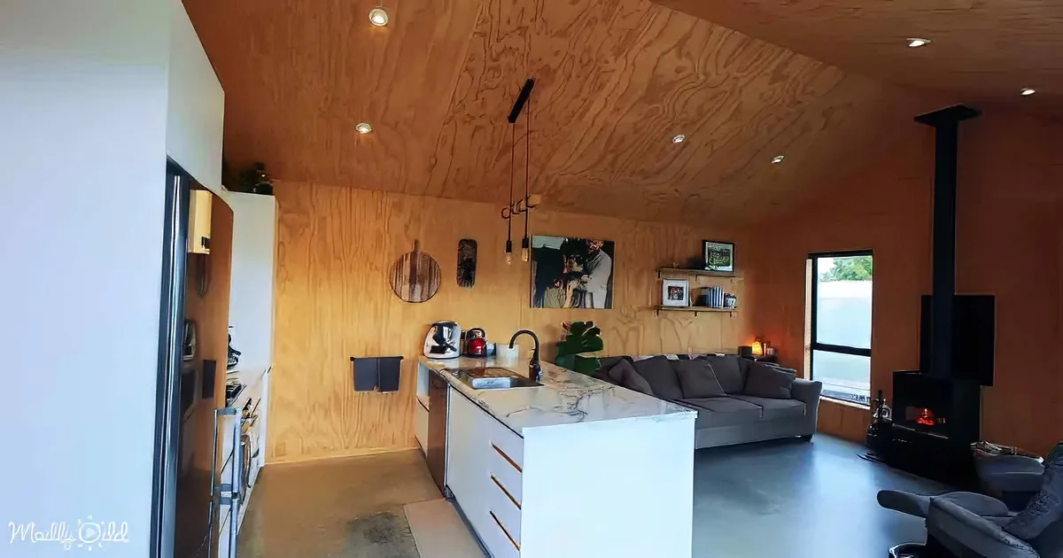 A cozy living space with wood-paneled walls, a kitchen island, and a wood-burning stove.