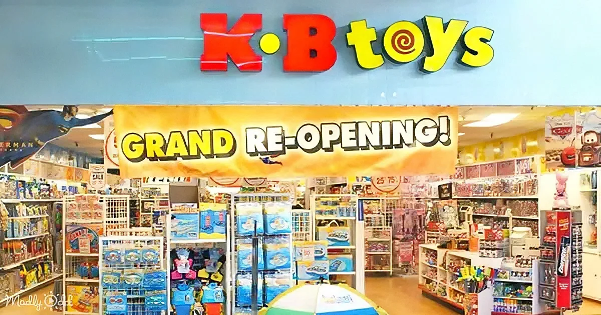 K-B Toys store with "Grand Re-Opening!" banner, colorful toys on shelves, and bright interior lighting.
