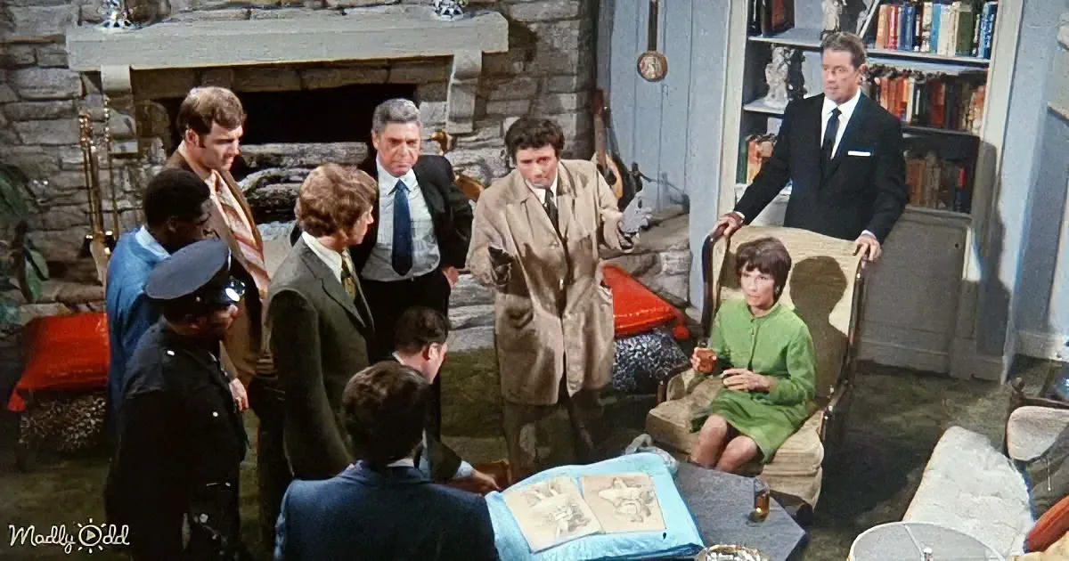A man in a trench coat stands in a room with others, seemingly in a discussion or confrontation.