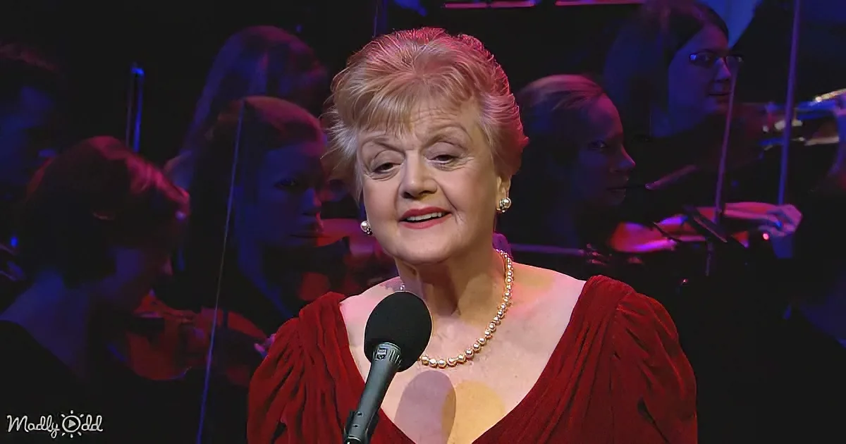 A woman in a red dress sings into a microphone, surrounded by musicians in a dimly lit setting.