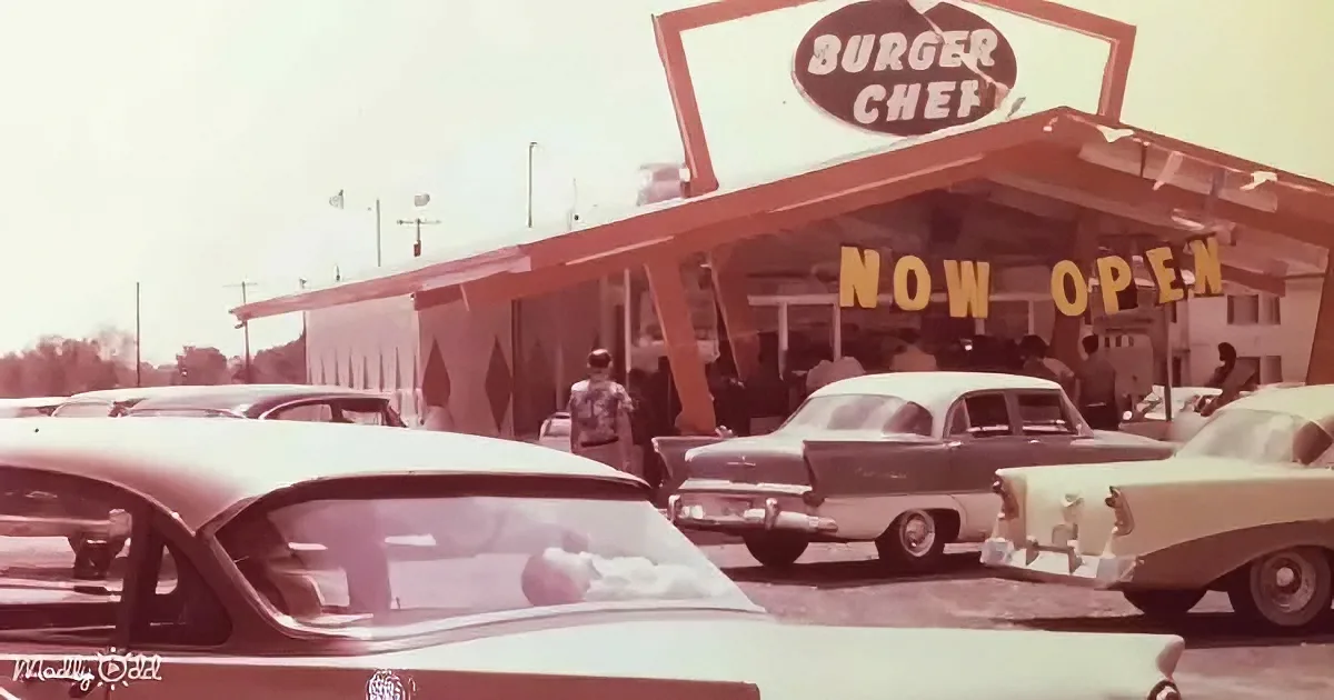 Burger Chef sign with "Now Open" in yellow letters, vintage cars in foreground, people outside.