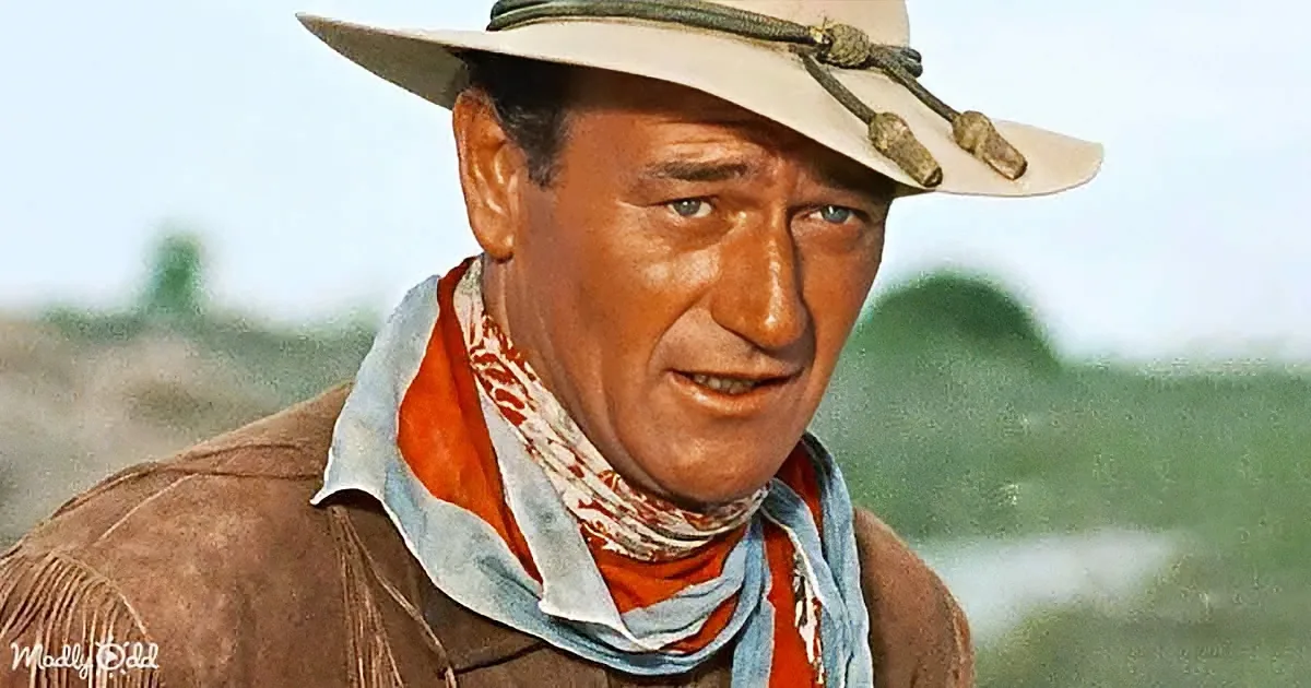 A man in a cowboy hat and western attire stands outdoors, looking to the side with a serious expression.