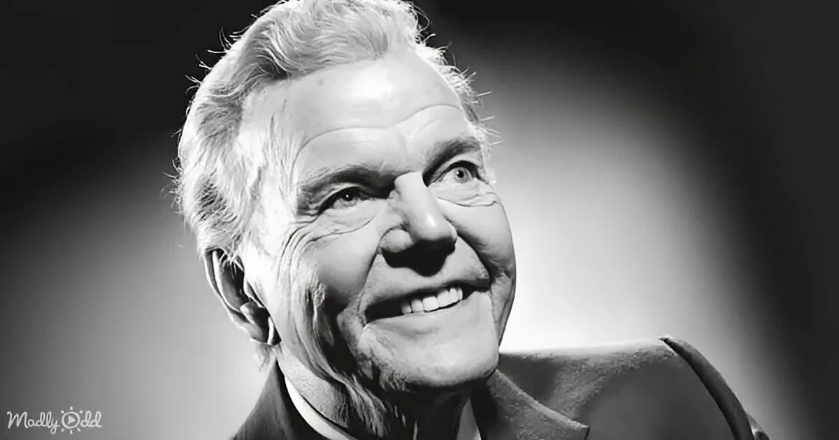 An older man with white hair and a warm smile, wearing a suit, is the main subject of this black and white photo.