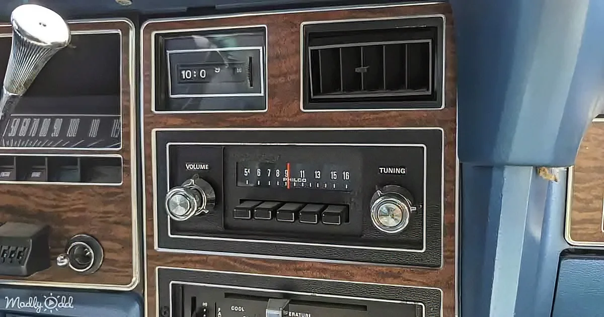 A vintage car dashboard with a radio, clock, and wood paneling.