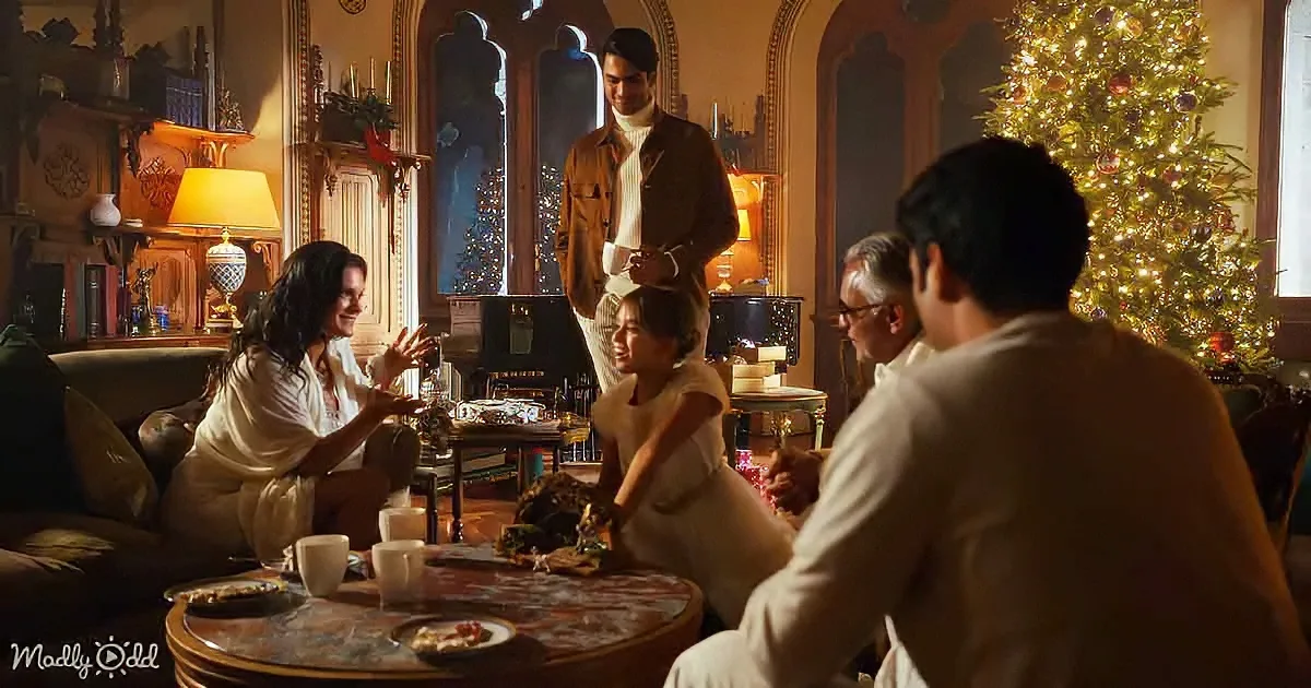 A family gathers around a table in a warmly lit room, celebrating with a Christmas tree in the background.
