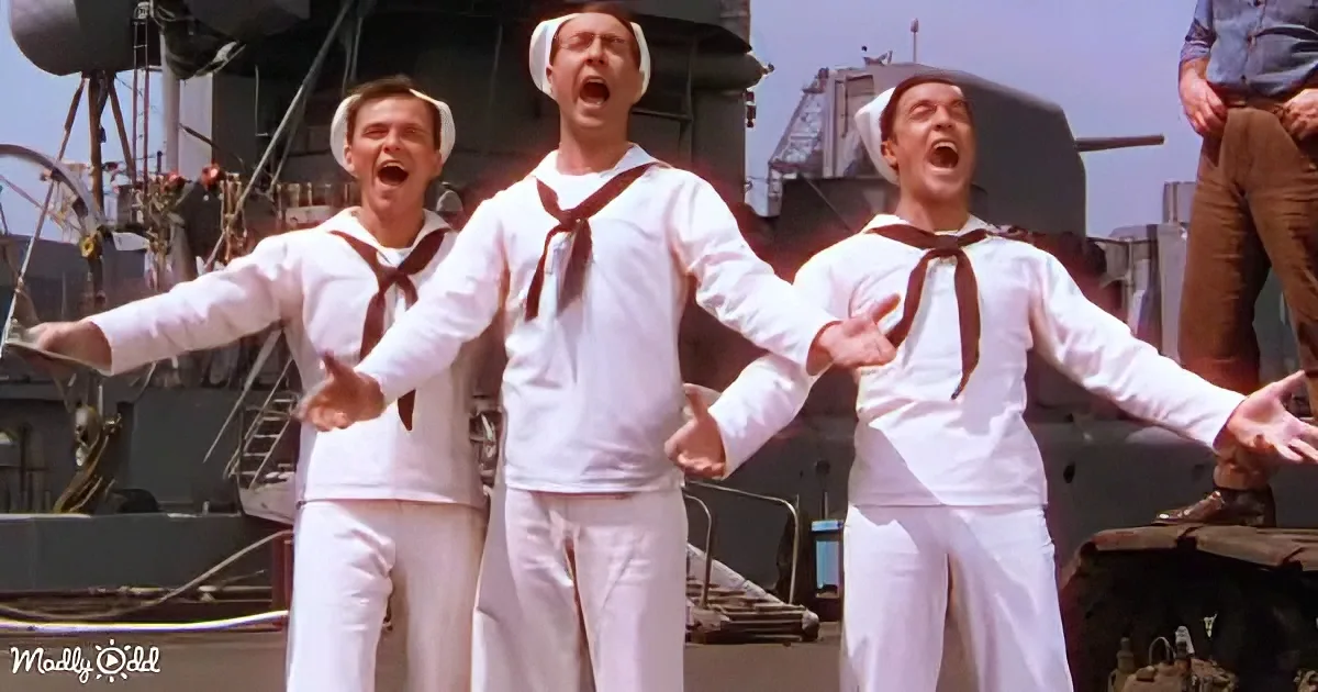 Three sailors in white uniforms sing passionately on a ship deck.