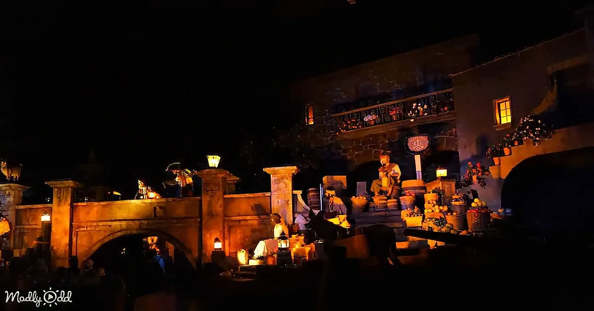 Figurines in costumes perform on a stage with warm lighting and a stone bridge in the background.