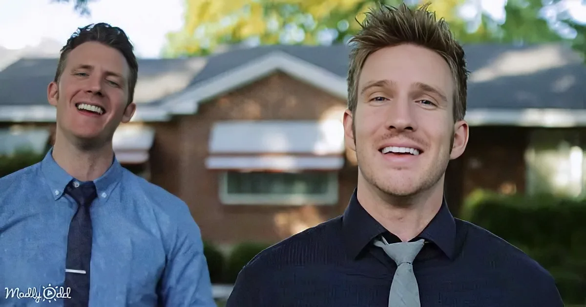 Two men in shirts and ties smile in front of a brick house with trees in the background.