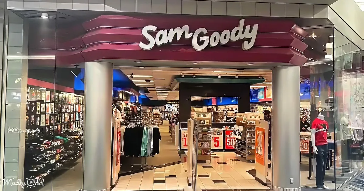 Sam Goody store entrance with merchandise, clothing racks, and sale signs visible inside.