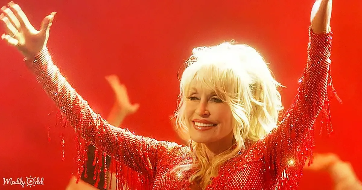 Dolly Parton in a red sequined outfit, arms raised, smiling against a red background.