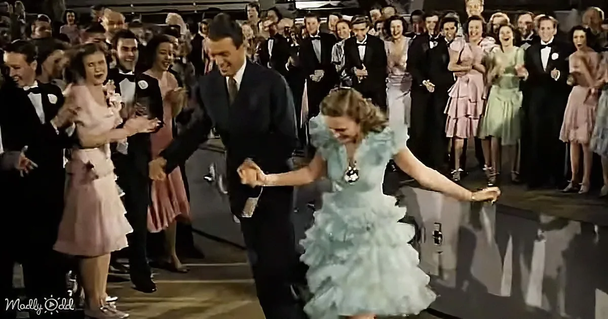 A man and woman in formal attire dance joyfully in front of a cheering crowd at a formal event.