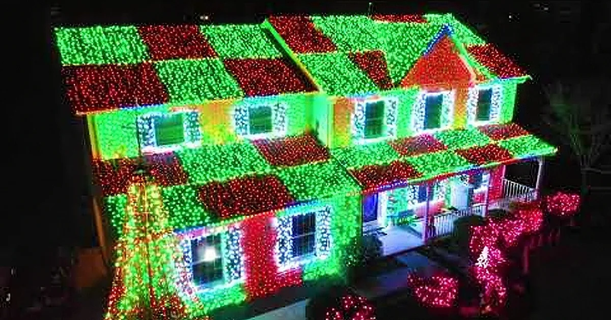 A house adorned with vibrant Christmas lights and festive decorations, including a lit-up tree and holiday figurines.