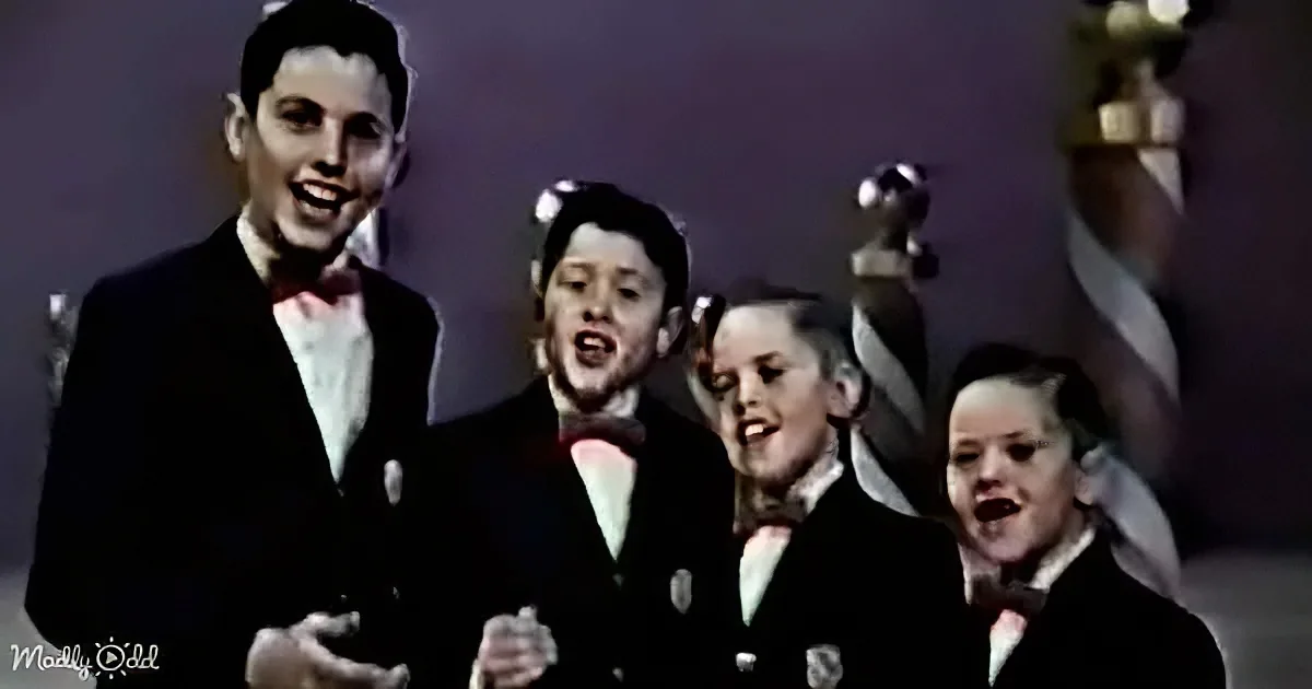 A group of children in formal attire sings together, with one child in the foreground gesturing.