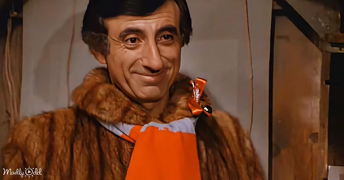 A man in a brown fur coat with an orange scarf smiles warmly, holding a bag.