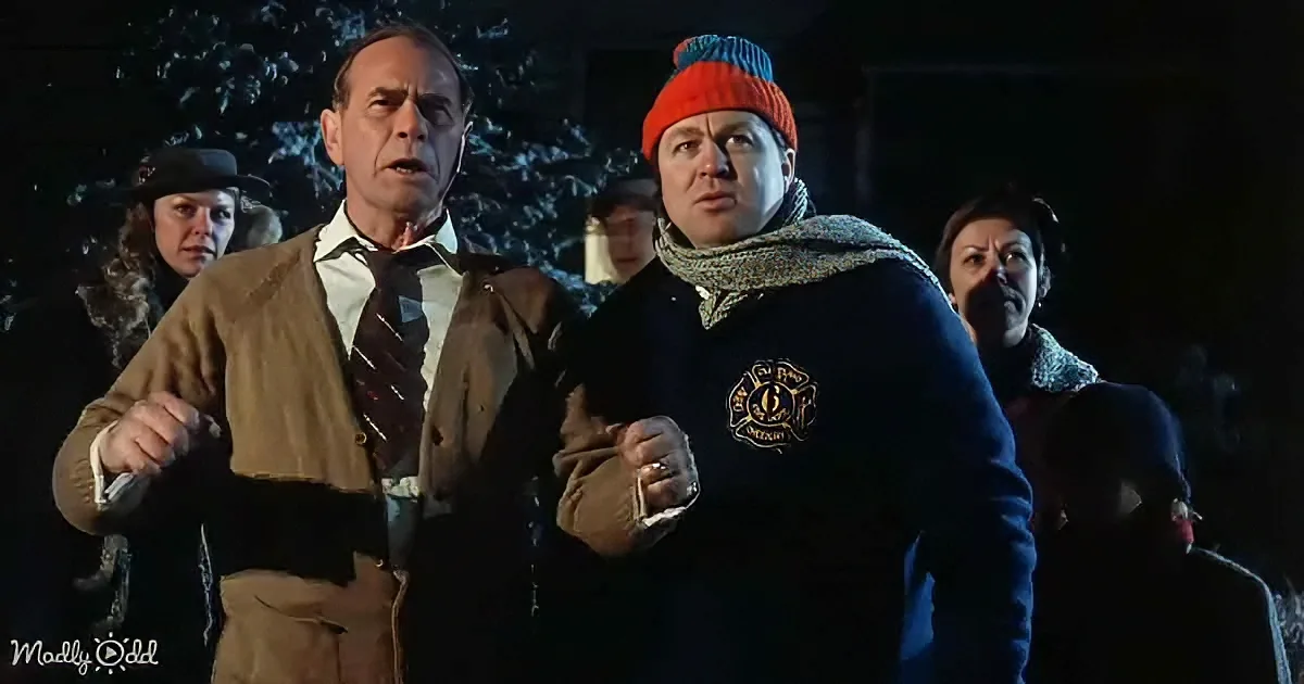 A man in a brown sweater and another in a blue jacket with a red beanie stand together, surrounded by others in winter...