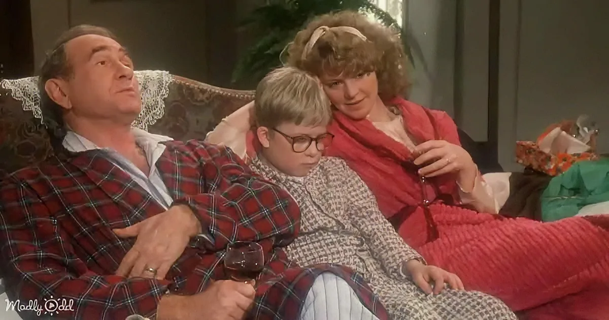 A man in plaid pajamas lounges on a couch with a young boy and a woman, all appearing relaxed.