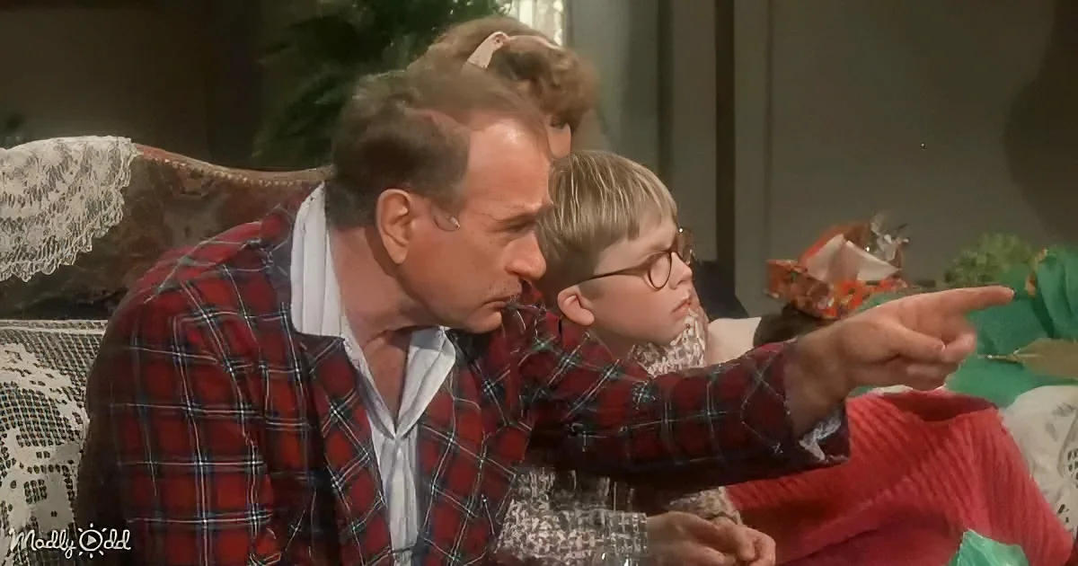 A man in a red plaid shirt leans over a young boy with glasses, pointing at something off-screen.