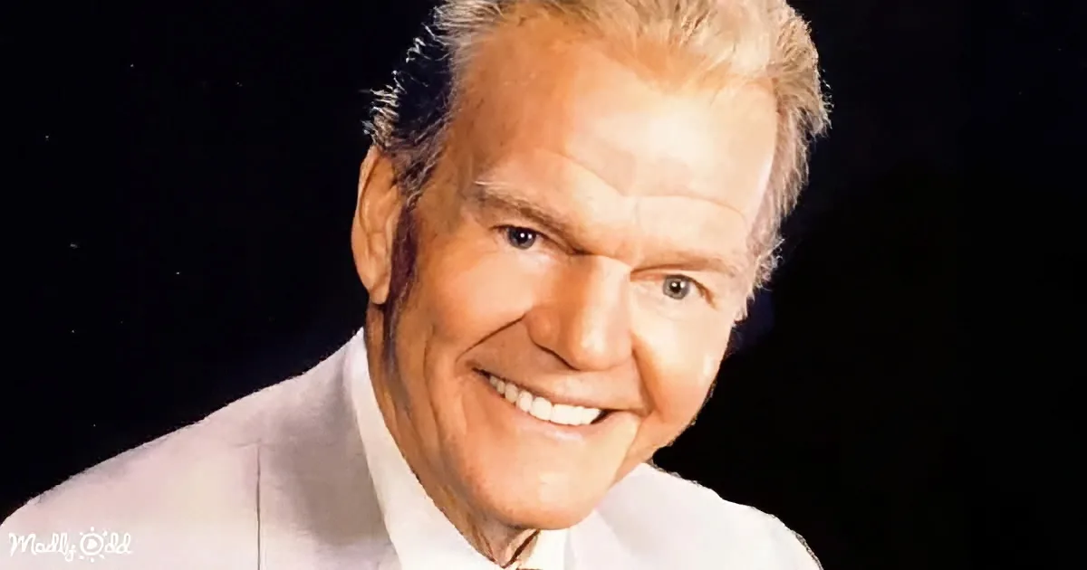 A smiling man with white hair, wearing a light-colored suit, against a dark background.