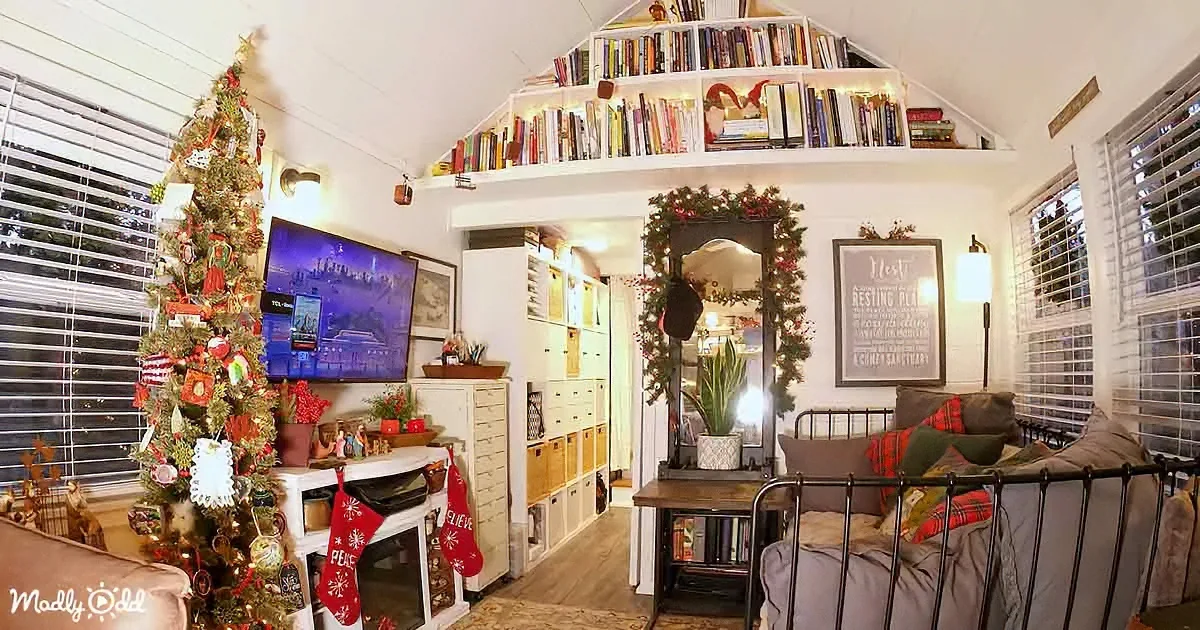 A cozy Christmas-decorated living room with a decorated tree, bookshelves, and festive decorations.