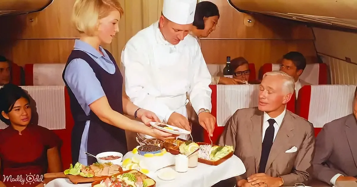 A chef serves food to a man in a suit at a dining table with a waitress nearby.