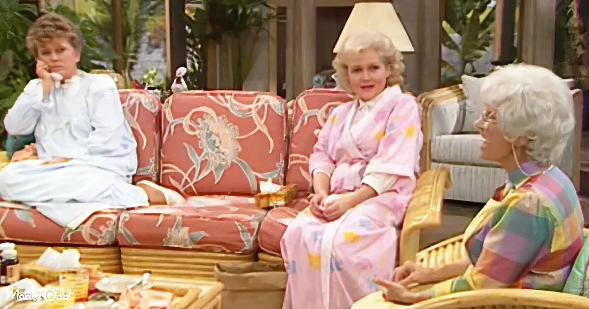 Three women in loungewear sit on a floral-patterned couch, engaged in conversation.