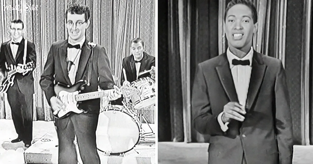 A man in a tuxedo plays guitar on stage, with another man singing nearby.
