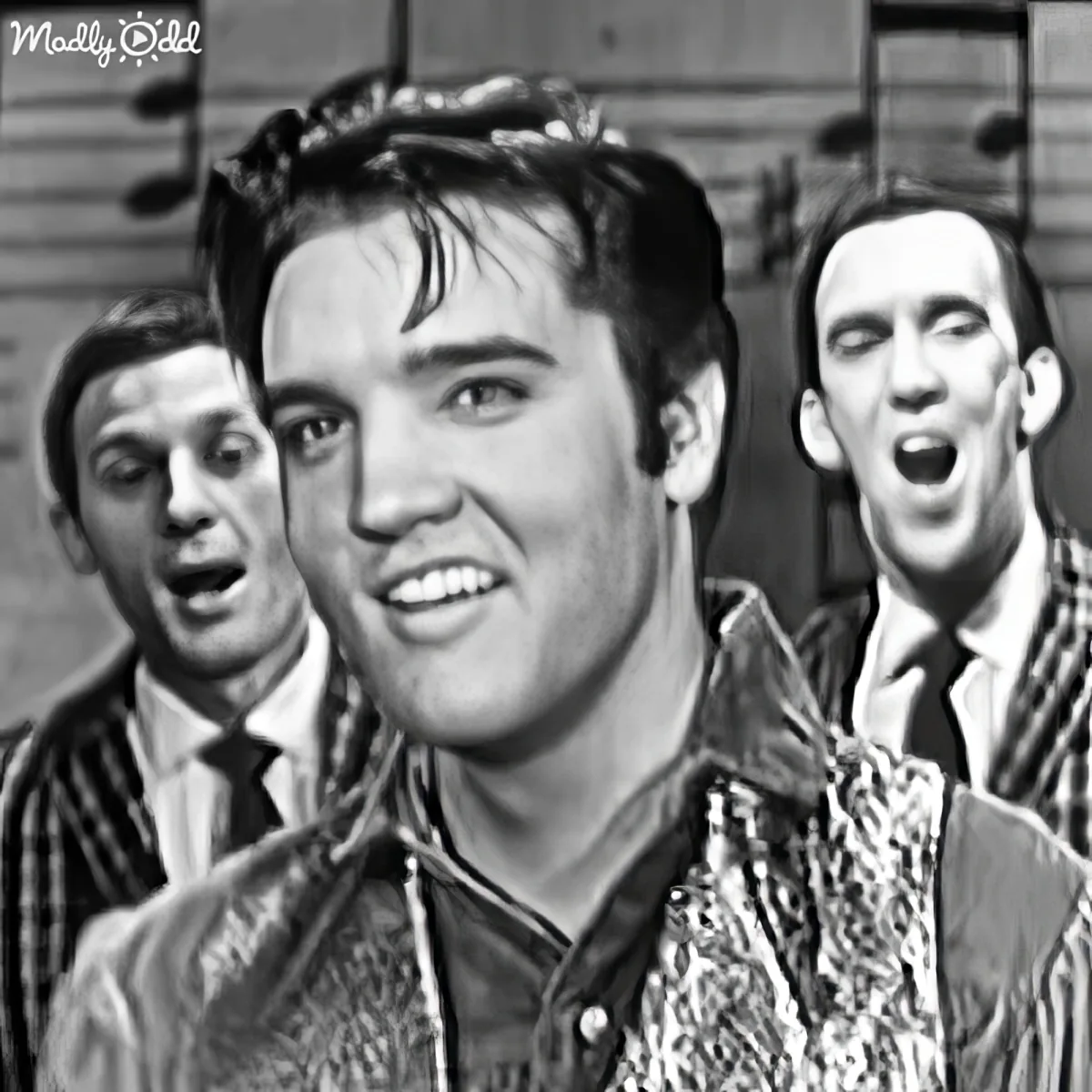Elvis Presley smiles in the foreground with two men singing behind him.