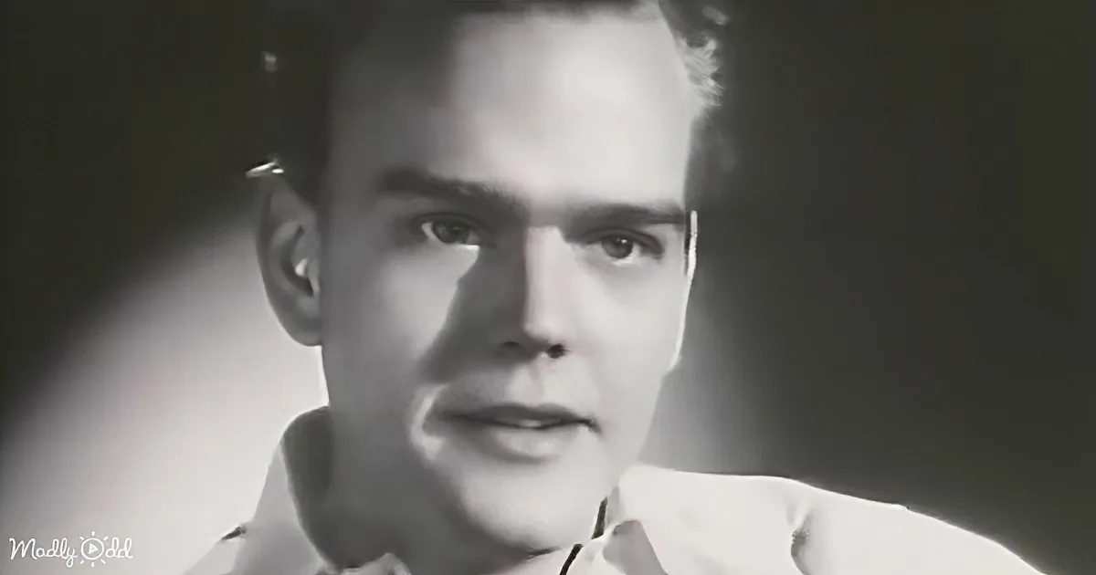 A man in a light-colored shirt with a dark background, looking directly at the camera.