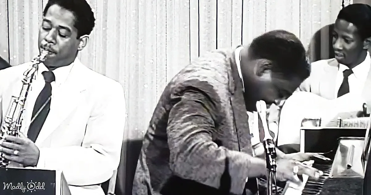 A man in a suit plays saxophone while another in a patterned jacket plays piano in a jazz setting.