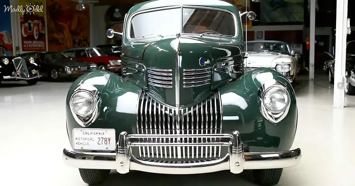 A vintage green car with a California historical vehicle license plate is displayed in a showroom.