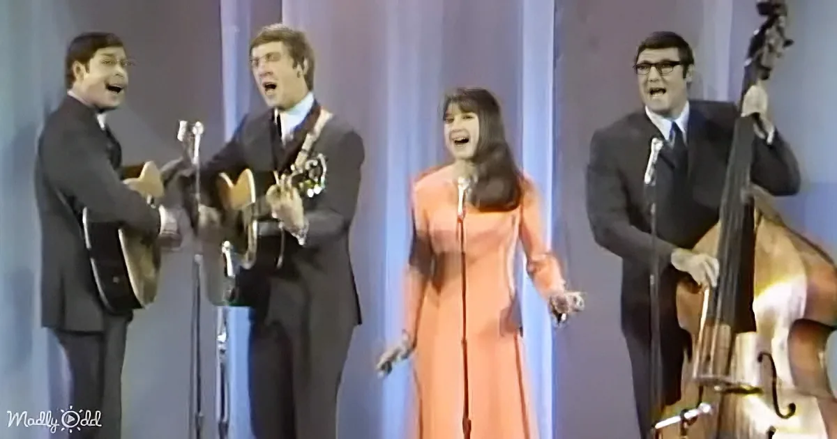 A woman in an orange dress sings on stage with three men playing instruments.