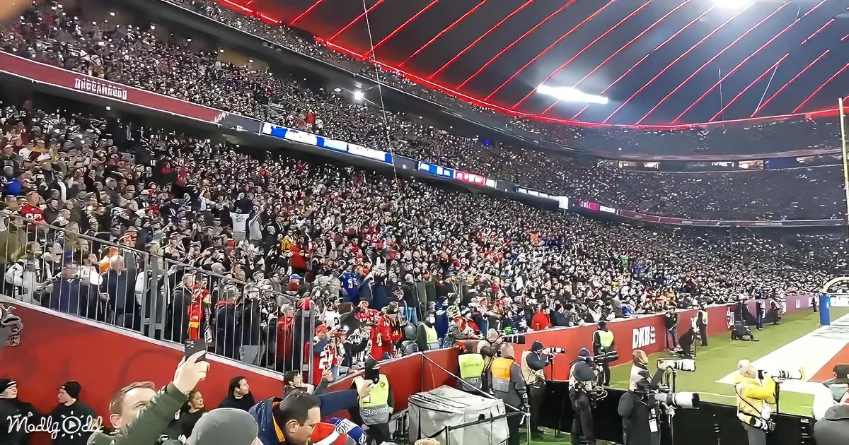 A large crowd of spectators fills a stadium, cheering and watching a sporting event.