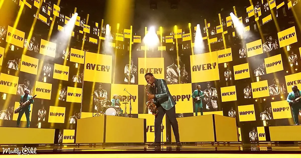 A saxophonist performs on stage with a vibrant yellow backdrop and "HAPPY" text.