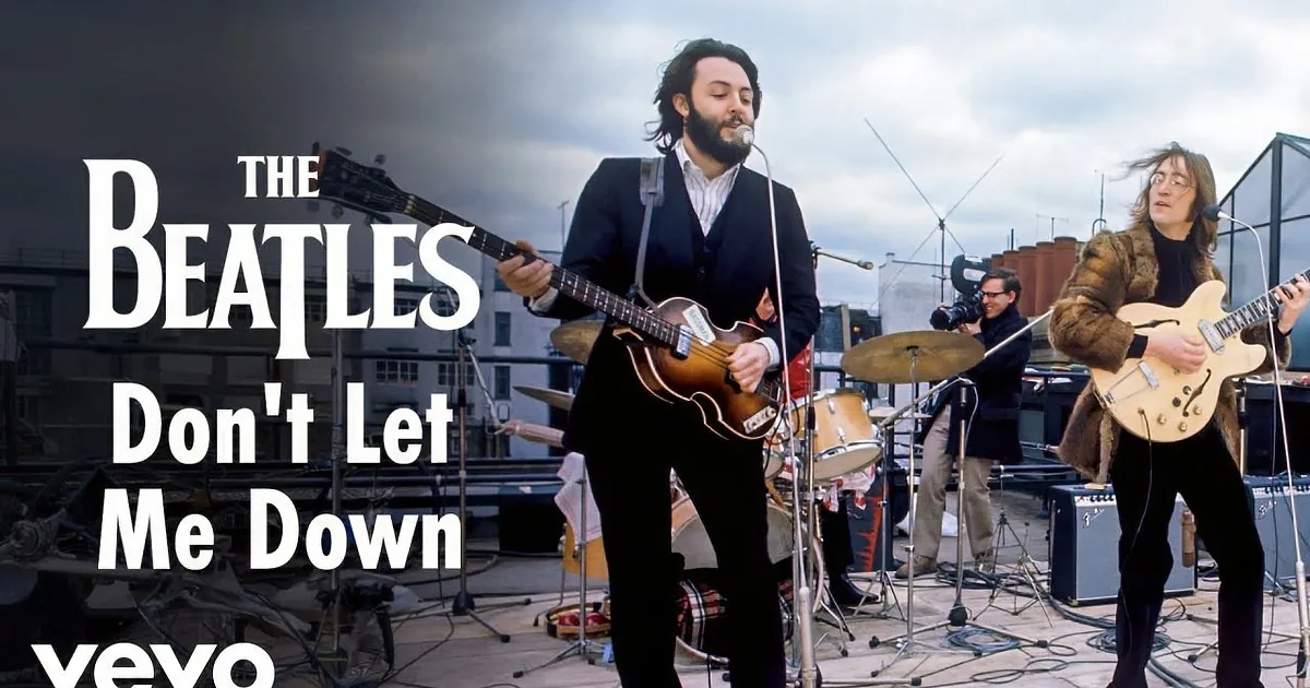 A man in a fur coat plays guitar on a rooftop, surrounded by other musicians and an audience.