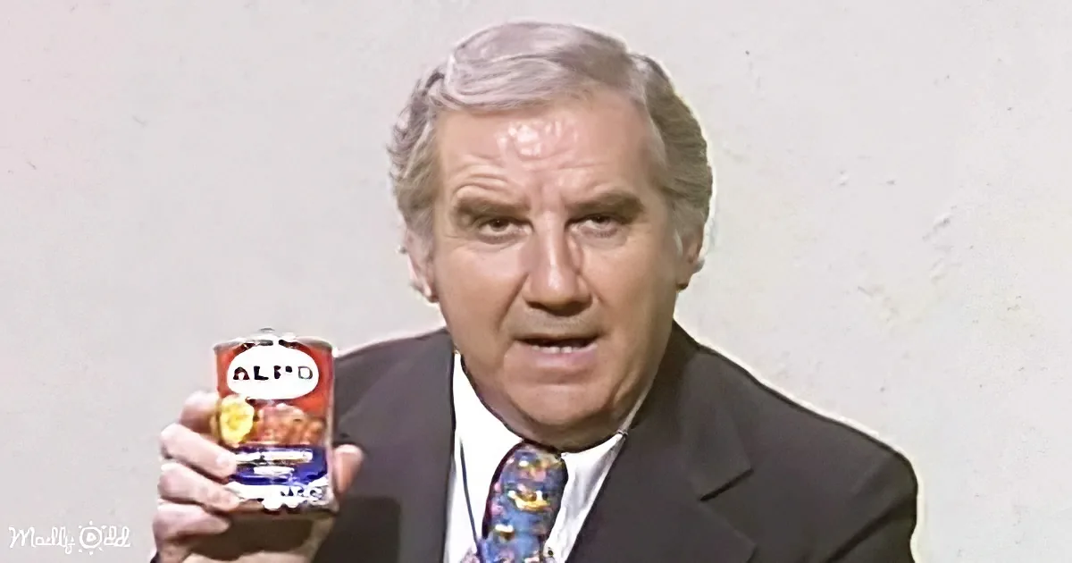 A man in a suit holds a can of Alpo dog food, looking directly at the camera.