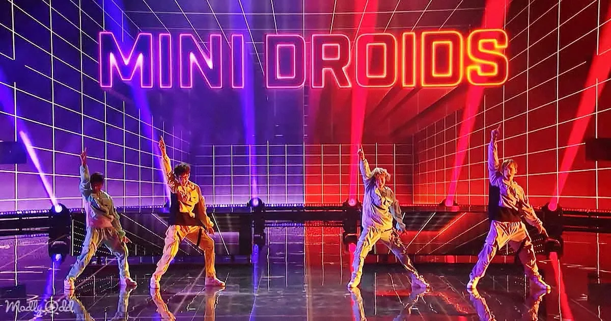 Four dancers in a synchronized pose on a stage with "MINI DROIDS" in neon lights.
