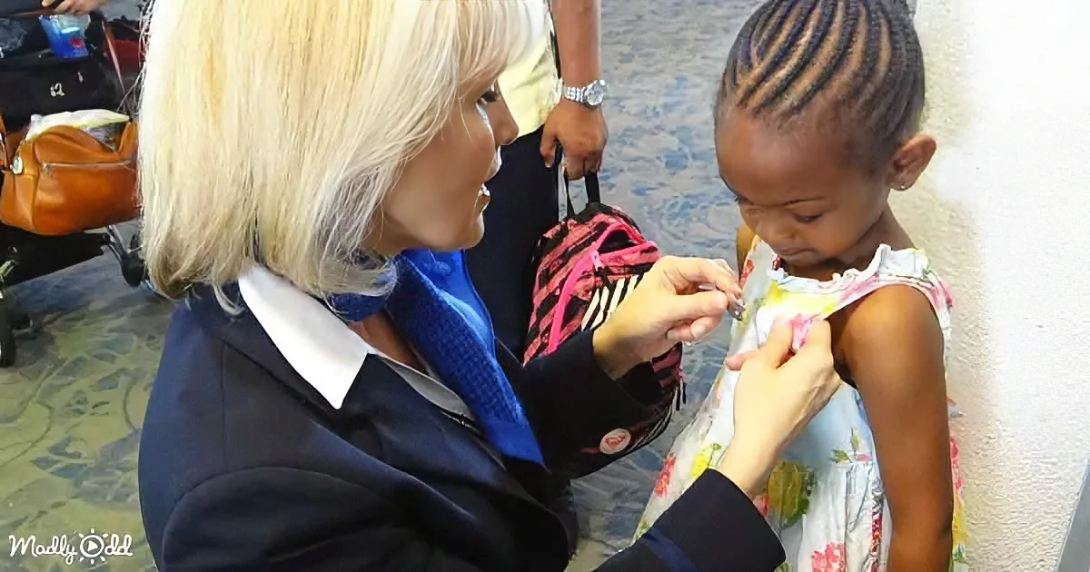 A woman in a uniform is pinning a badge on a young girl's dress.