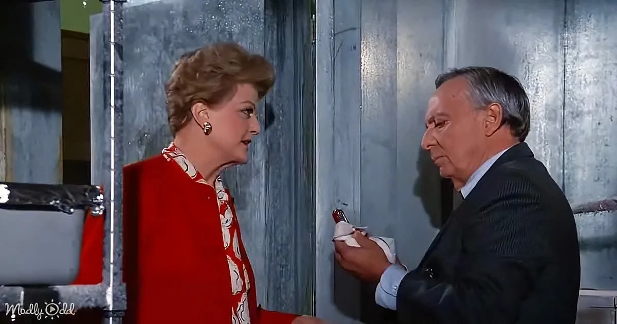 A woman in red and white dress stands facing a man in a suit holding a red object.
