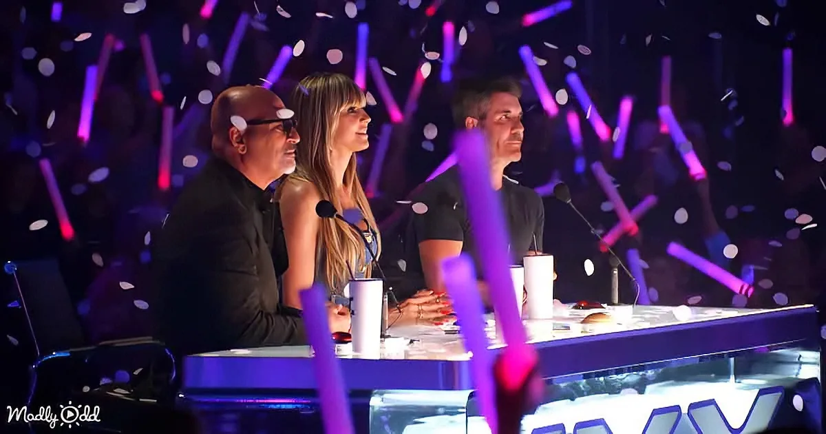 Three judges sit at a table with microphones and confetti falling around them.