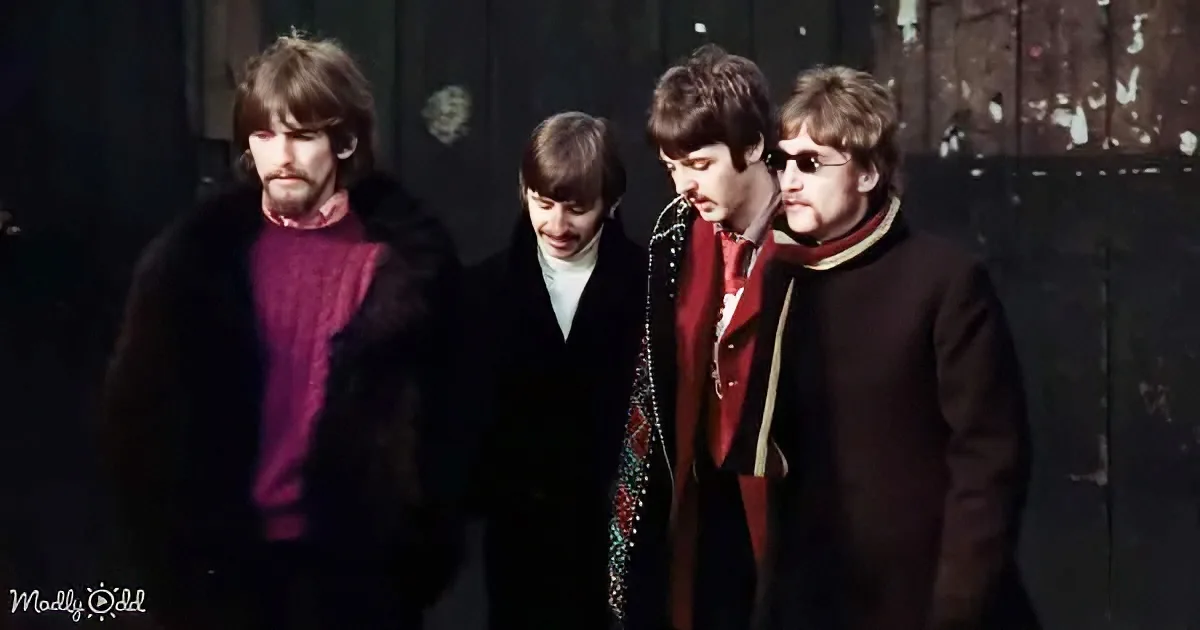 Four men in winter coats, one with sunglasses, walking together, possibly The Beatles.