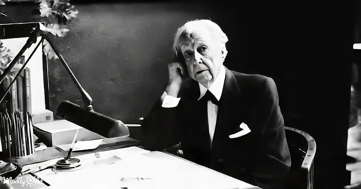 An older man in a suit sits at a desk with a lamp, surrounded by books and papers.