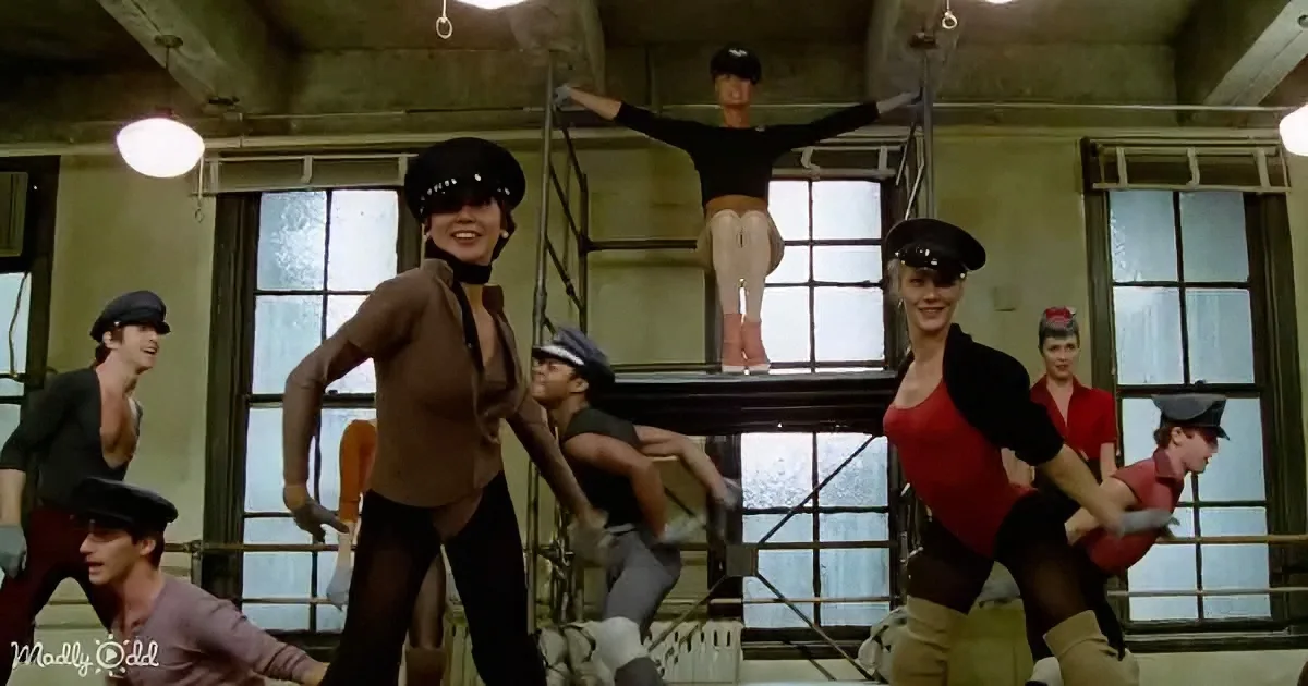 Audrey Hepburn leads a group of dancers in a synchronized routine in a dance studio.