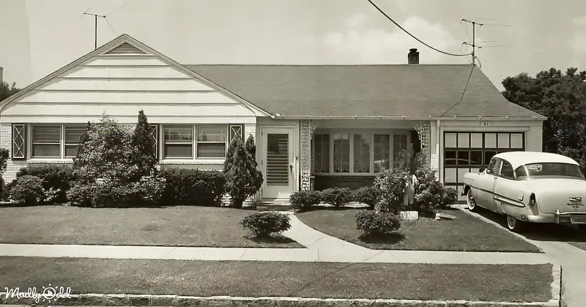 A vintage suburban home with a white car parked in front, surrounded by neatly trimmed bushes and a driveway.