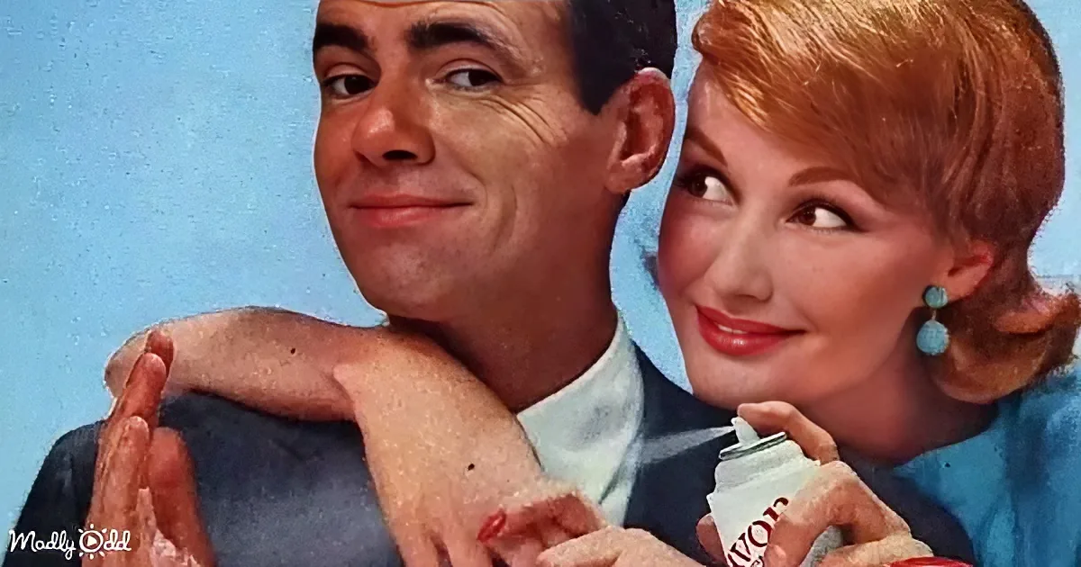 A man and woman are embracing, the woman holding a bottle, both smiling and looking to the side.