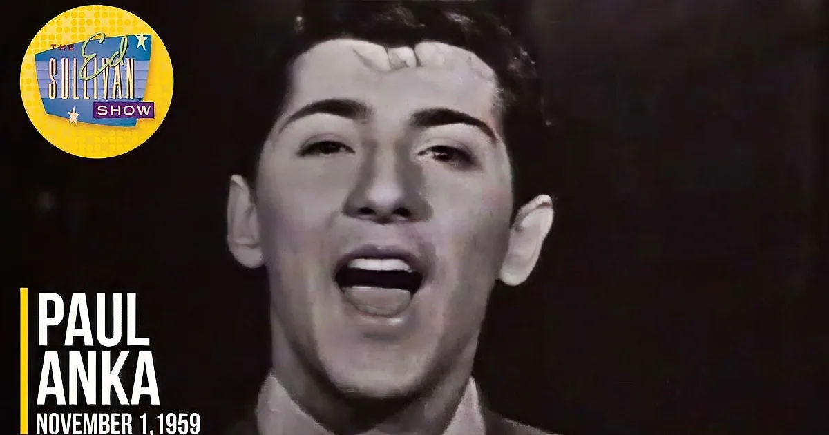 A man with styled hair and a light-colored shirt is shown in a black-and-white image.