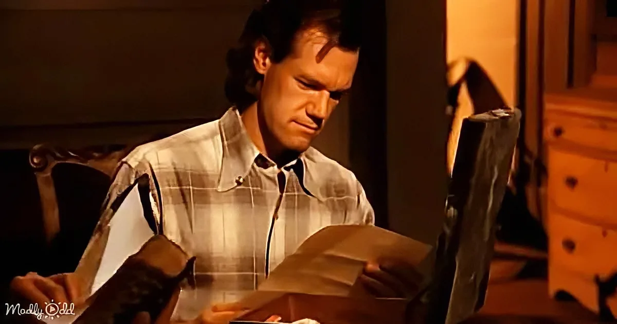 A man in a plaid shirt sits at a table, intently reading a book with a magnifying glass.