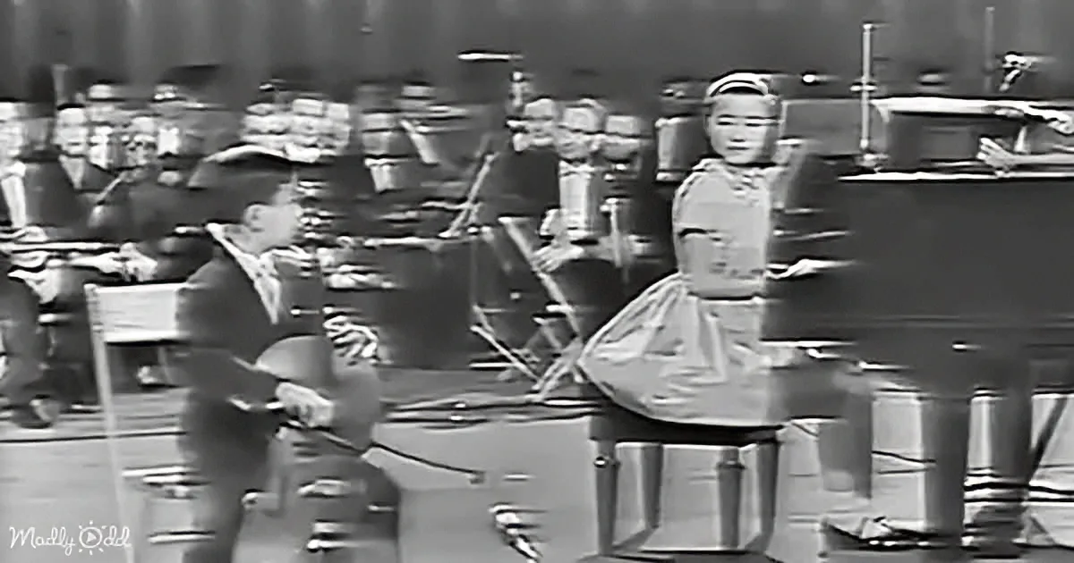 A man and woman dance in front of an orchestra in a vintage setting.
