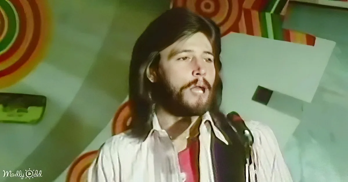 A man with long hair and a beard sings into a microphone, wearing a white shirt with a red tie, against a colorful, retro...
